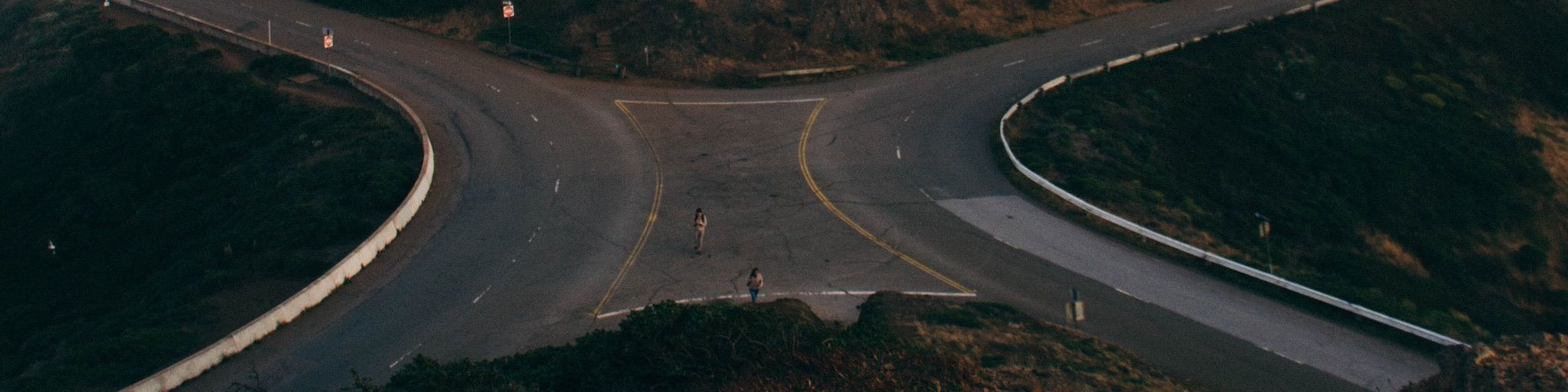Two people standing on a merging hill road